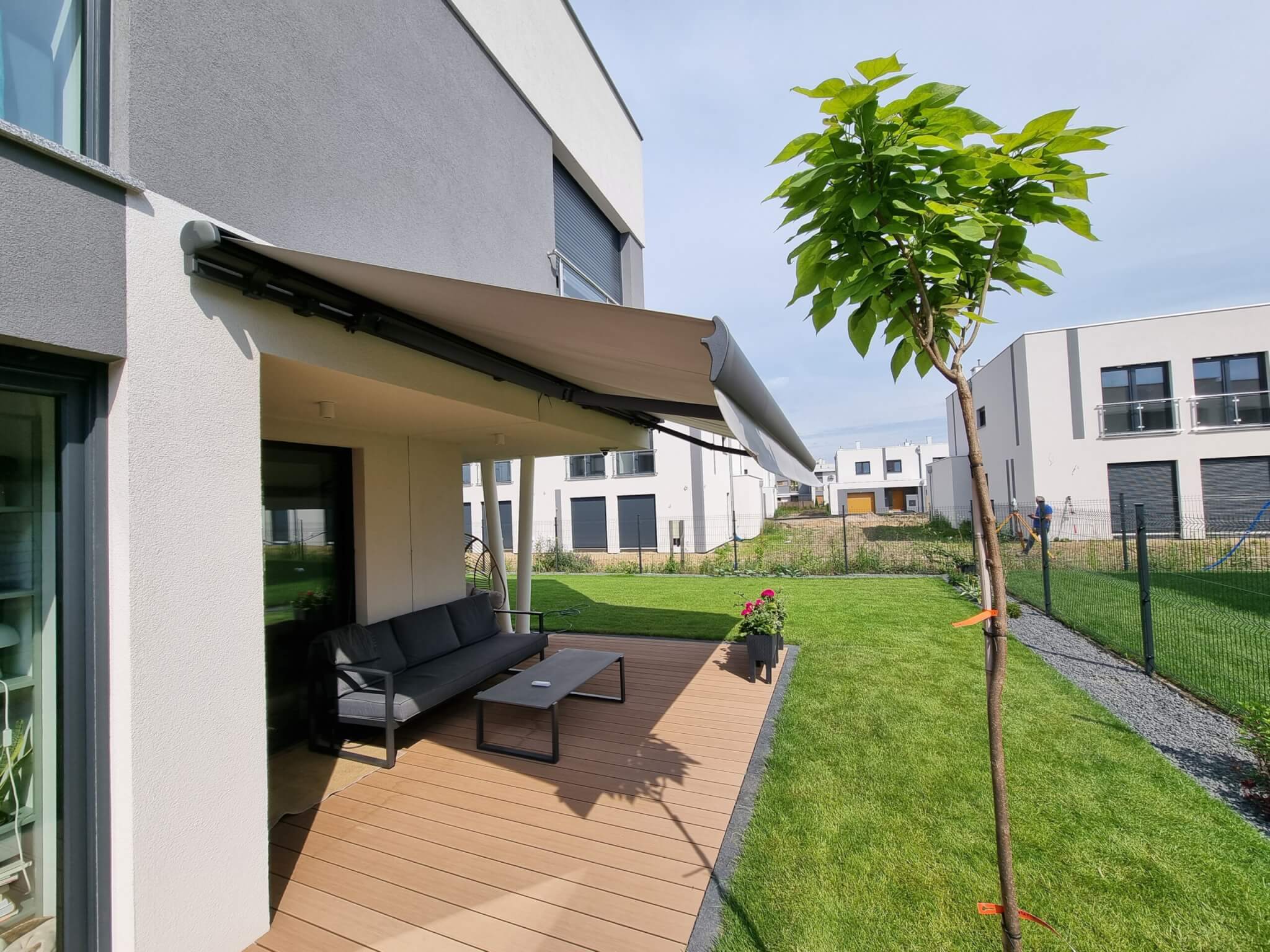 Nowoczesna szara markiza tarasowa bez kasety - aranżacja przy domu szeregowym