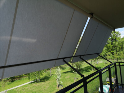 szara markiza balkonowa przymocowana do barierki balkonu